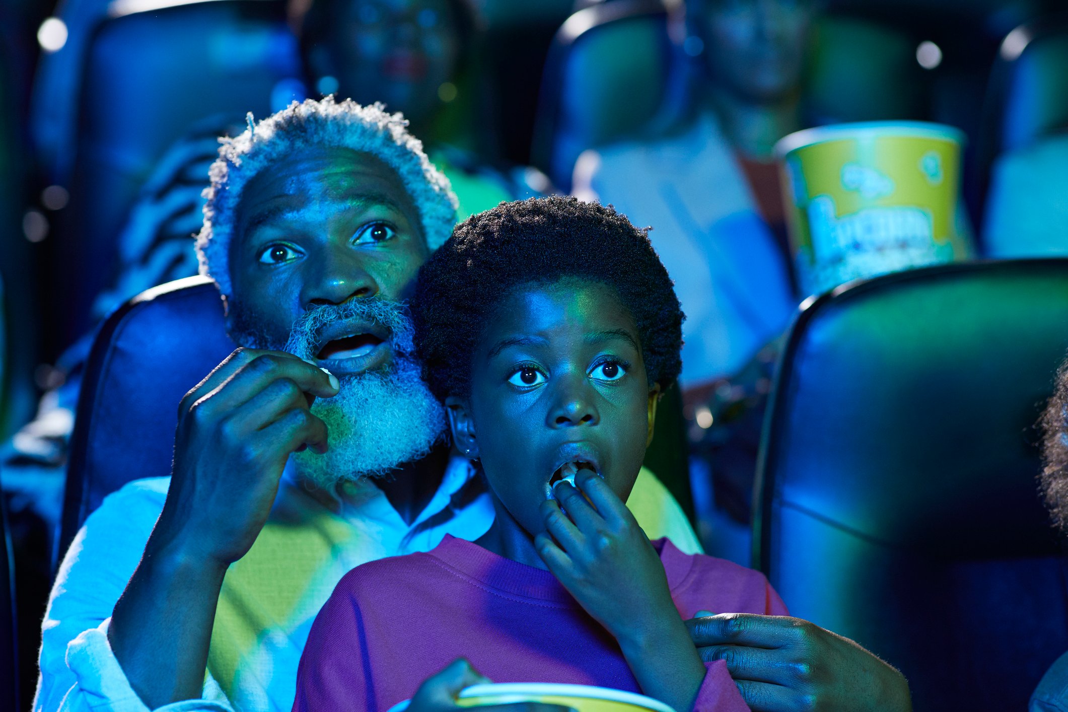 A man and a child watching a film in a theater.
