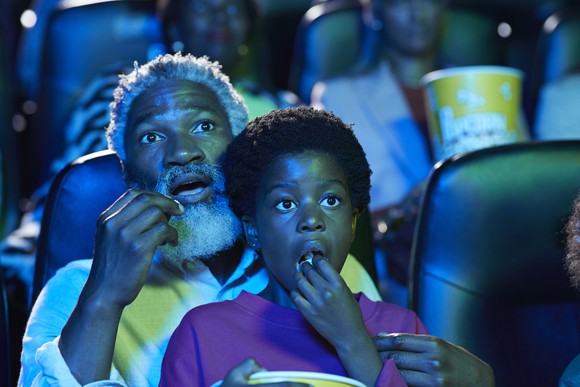 A man and a child watching a film in a theater.
