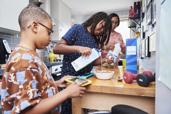 A family pouring milk into cereal bowls.