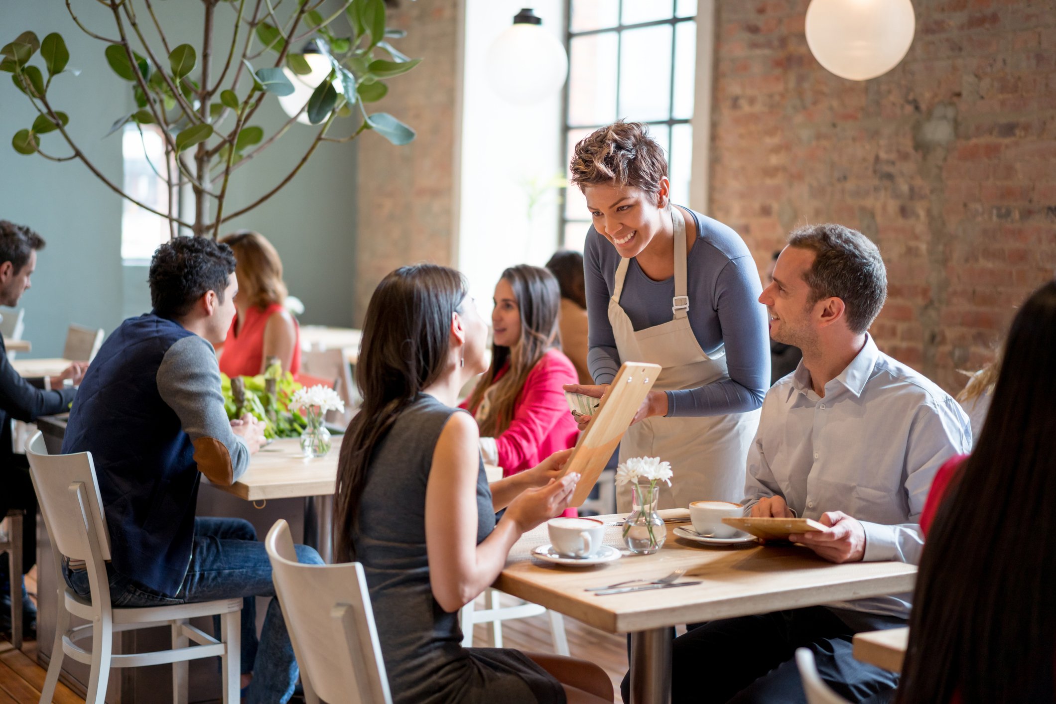 A waitress takes a couple's orders at a restaurant.