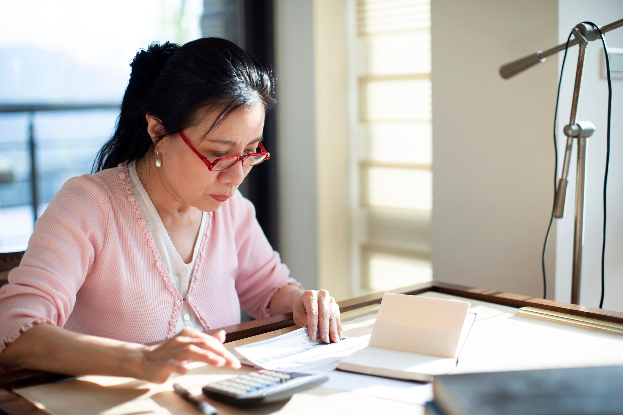A family member ponders personal finances on a desk at home.