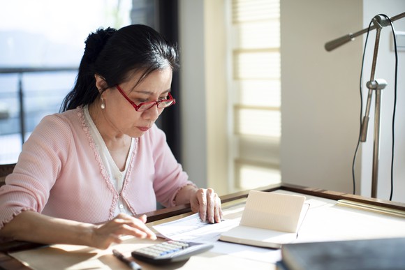 A family member ponders personal finances on a desk at home.