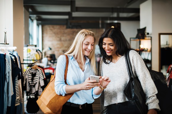 Two women shopping on their phone.
