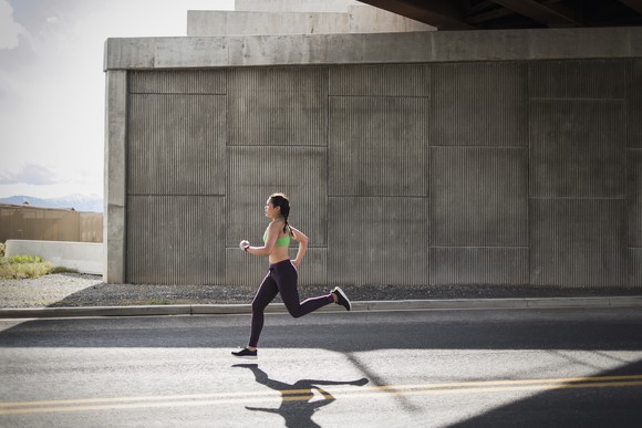 A person in workout gear running on a street.