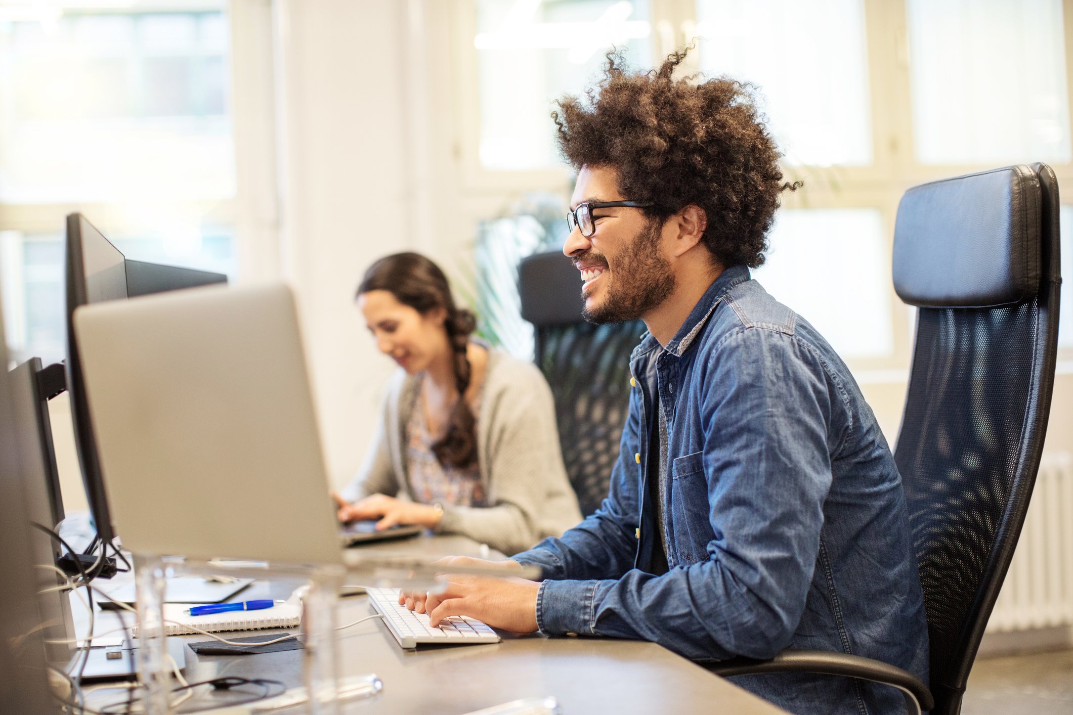 Two colleagues work at an open work station.