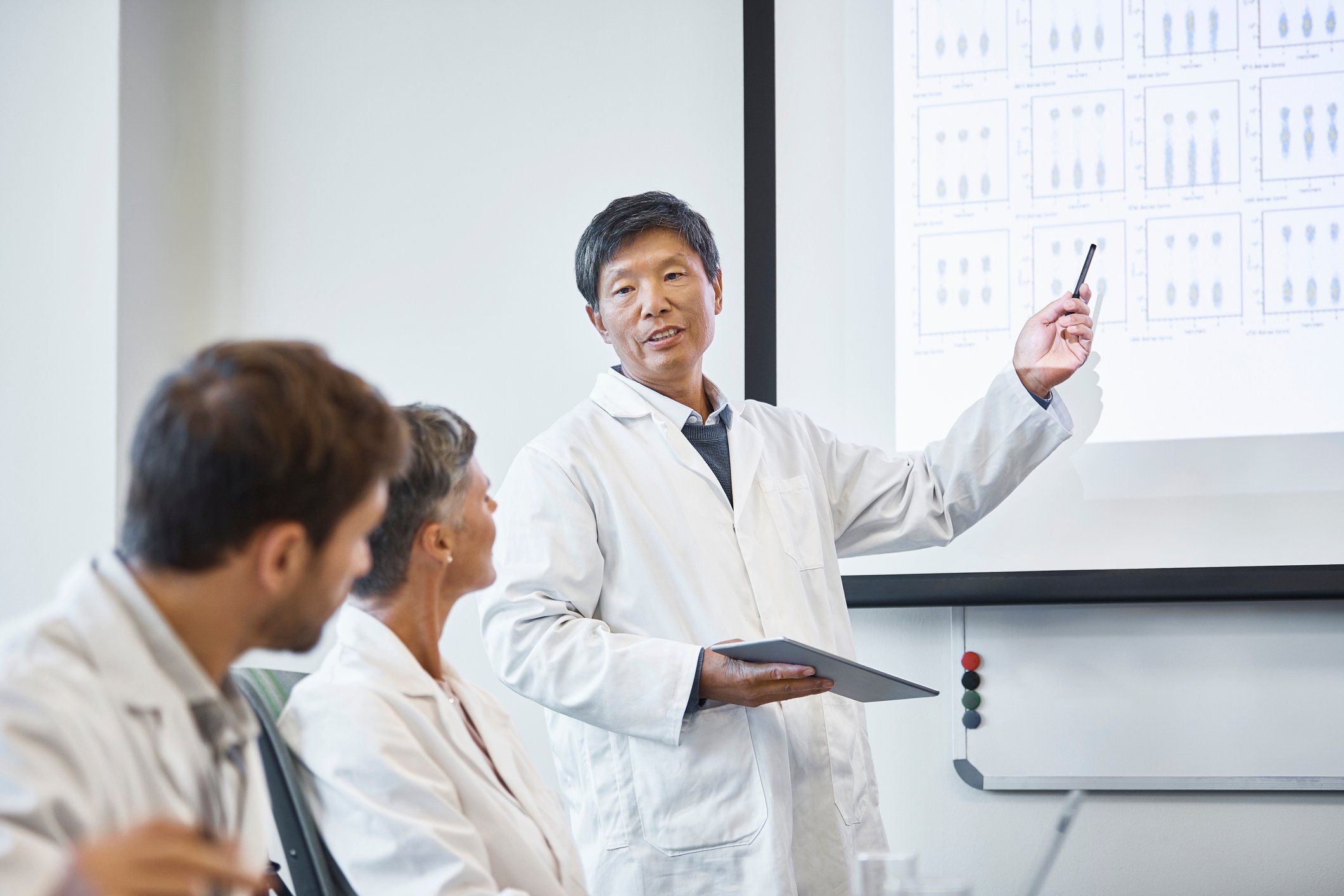 A researcher presenting data to colleagues on a big screen.