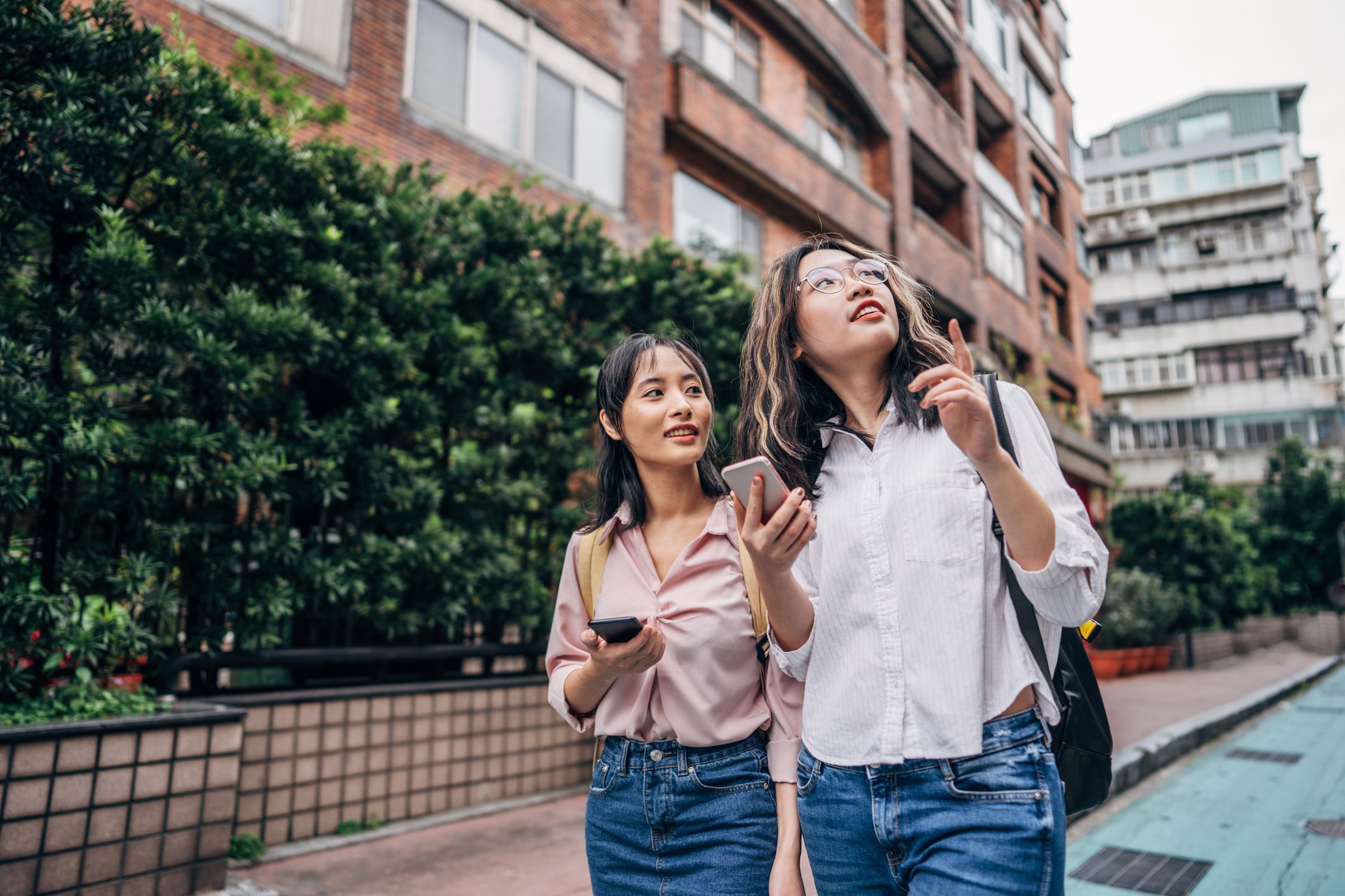 Two people holding smartphones look up at a nearby building