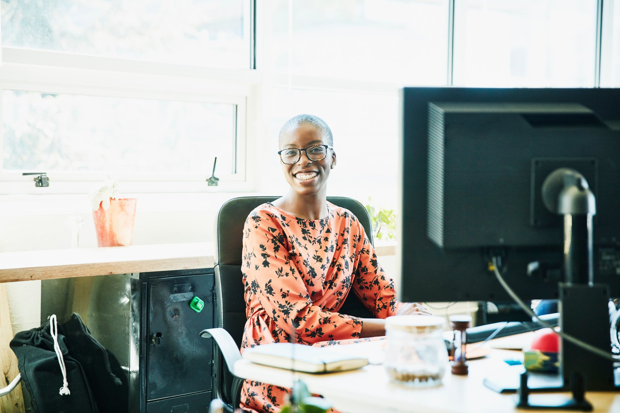 Businessperson sitting at computer in office and smiling.