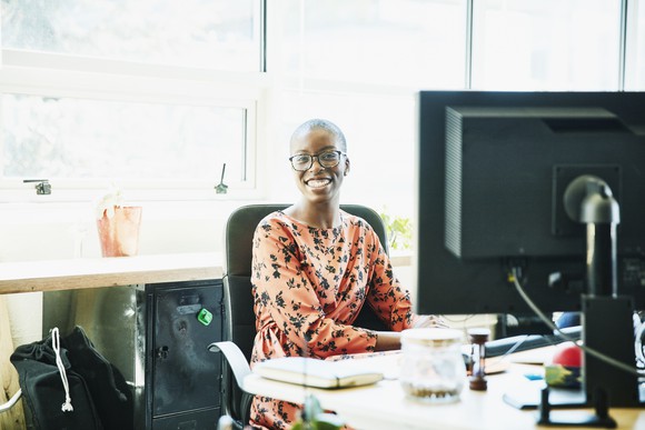 Businessperson sitting at computer in office and smiling.
