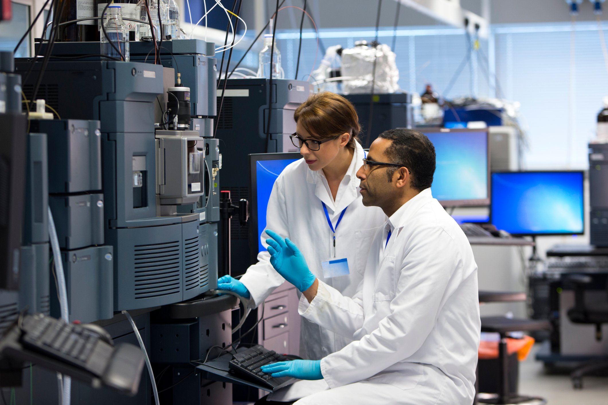 Two research scientists working in a lab with large equipment.