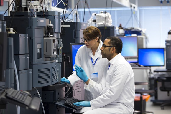 Two research scientists working in a lab with large equipment.