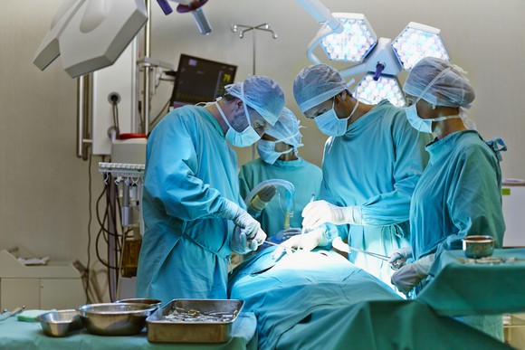 A team of surgeons performs surgery on a patient.