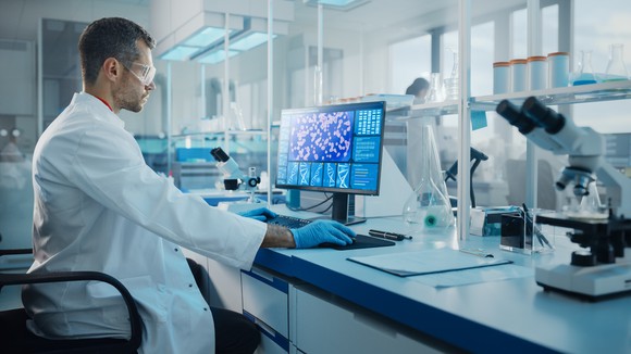 A scientist does research at a computer in a lab.