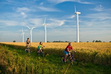 Children cycling past wind turbines.