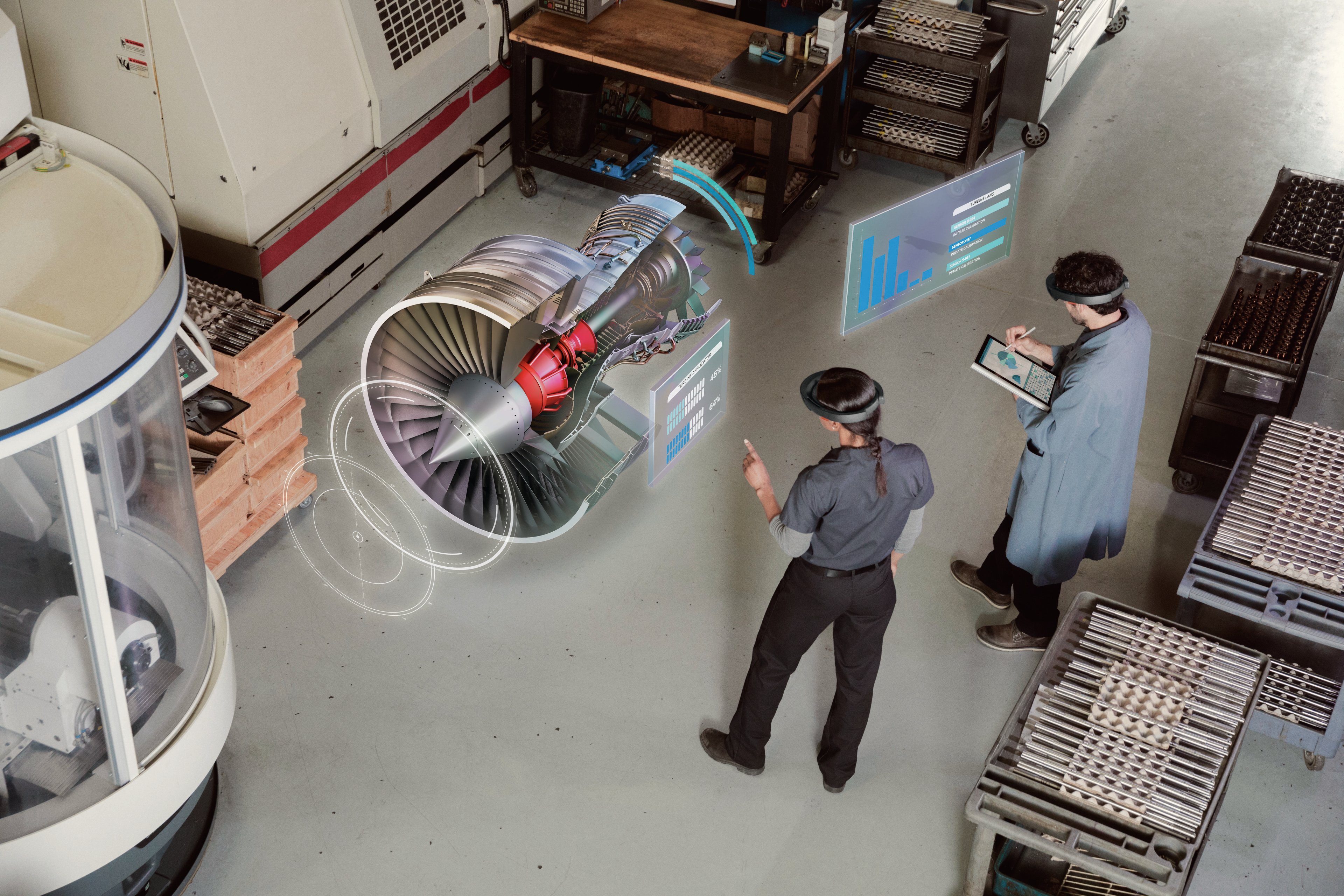 Two people wearing AR headsets view a 3D digital image of an engine in a warehouse.