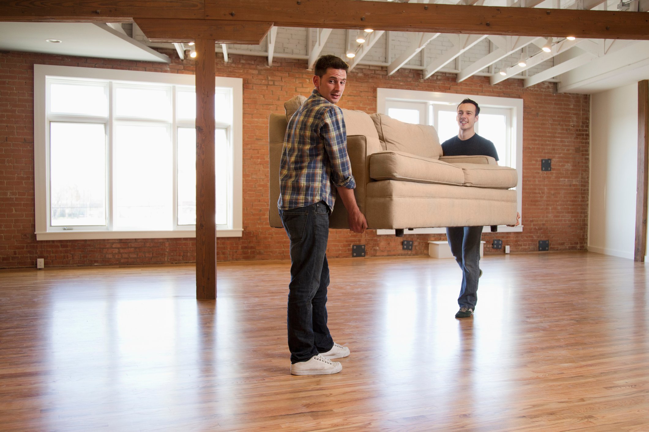 Two people moving a sofa in a flat.