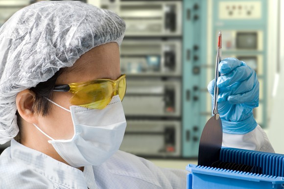 A technician inspects a silicone wafer in a sterile environment.