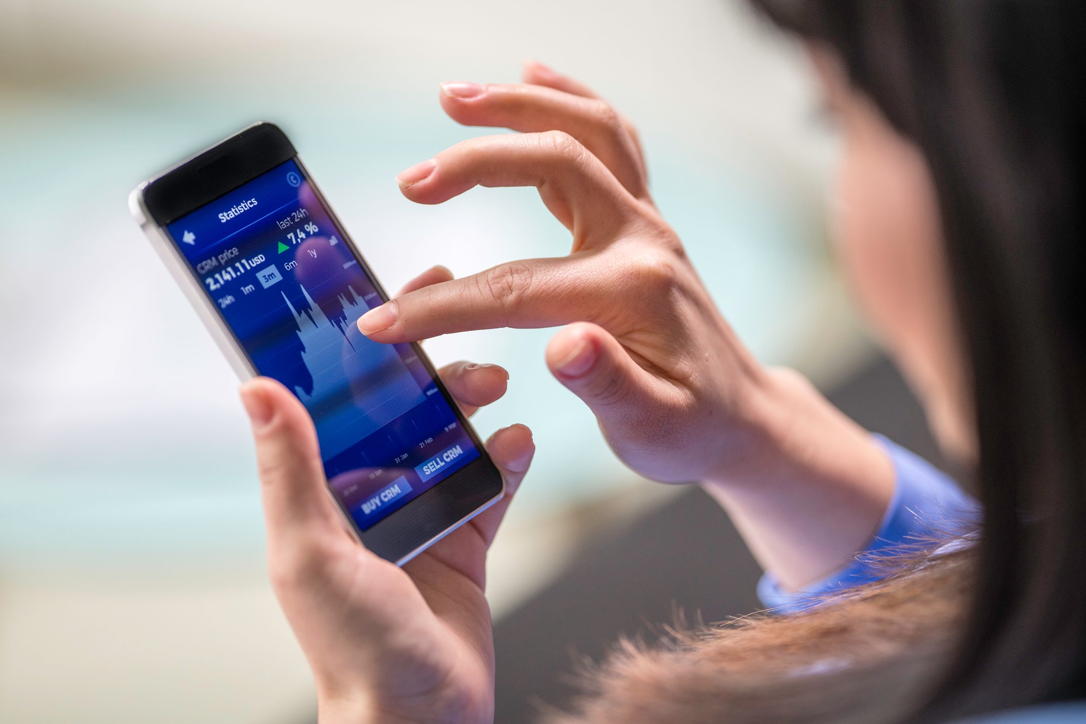 A person checks the price of an equity in a price graph on their phone.