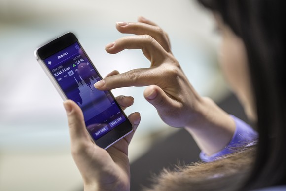 A person checks the price of an equity in a price graph on their phone.