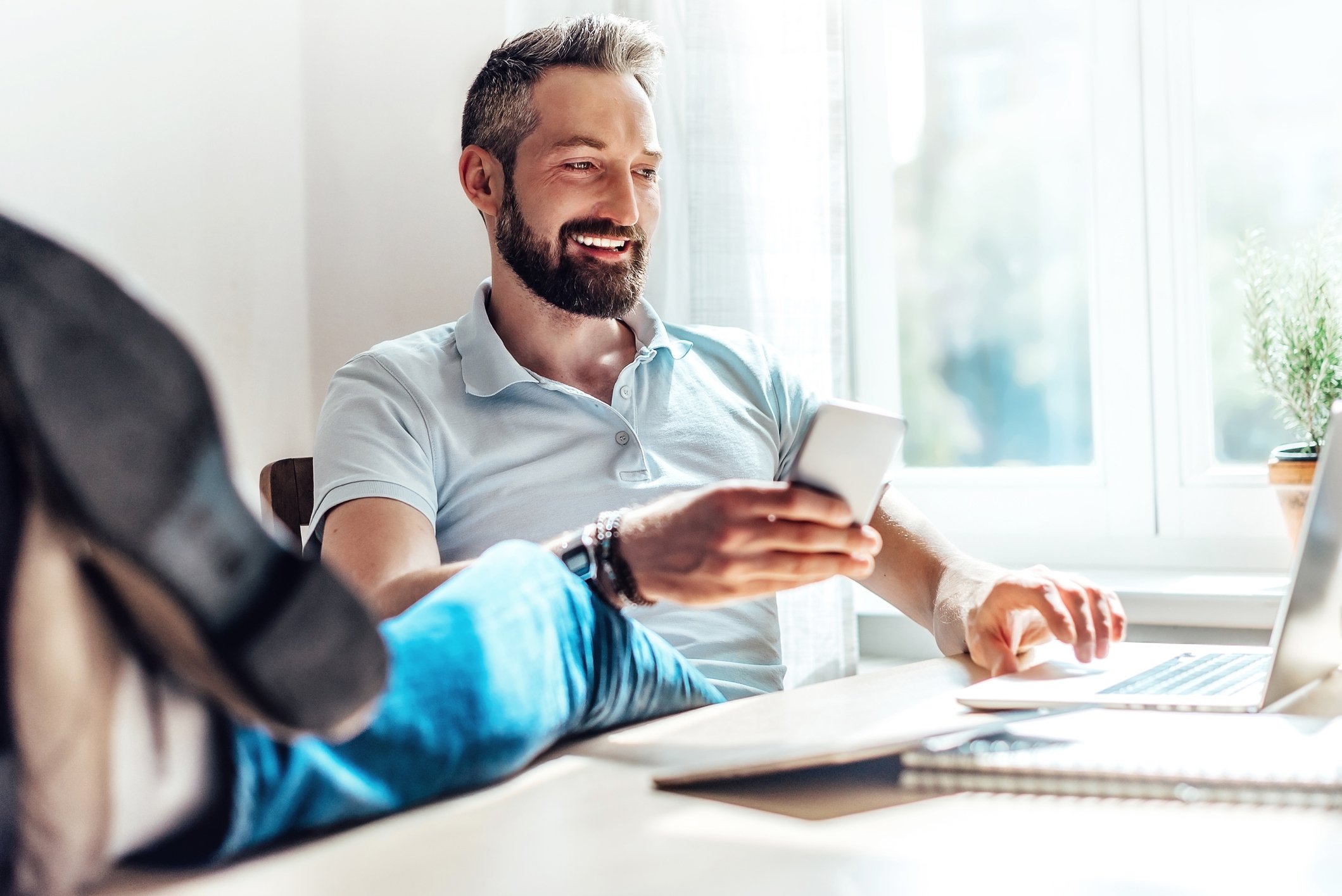Smiling bearded man looks something on his laptop.