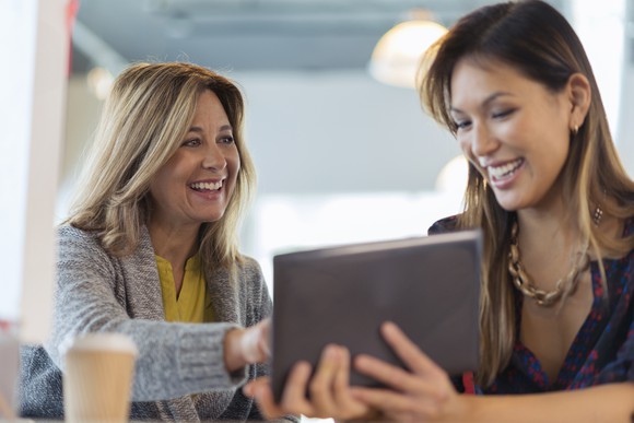 2 happy office workers using a digital tablet.