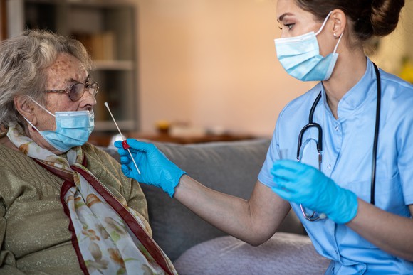 A clinician tests a patient for COVID.