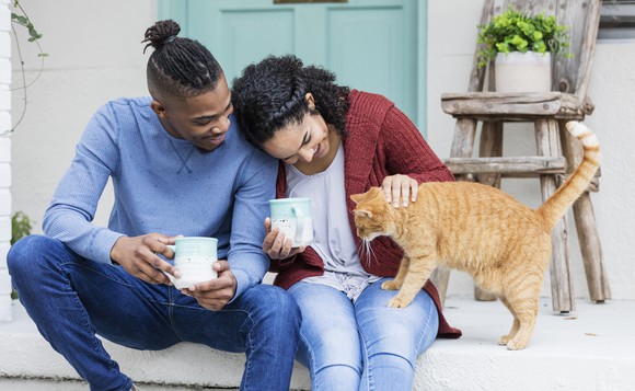 Two people sitting on a porch with a cat.