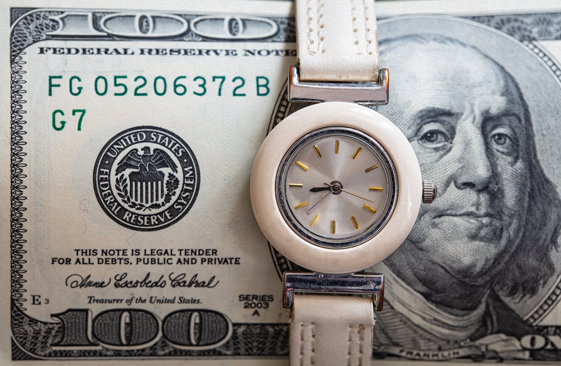 A wristwatch wrapped around a $100 bill.