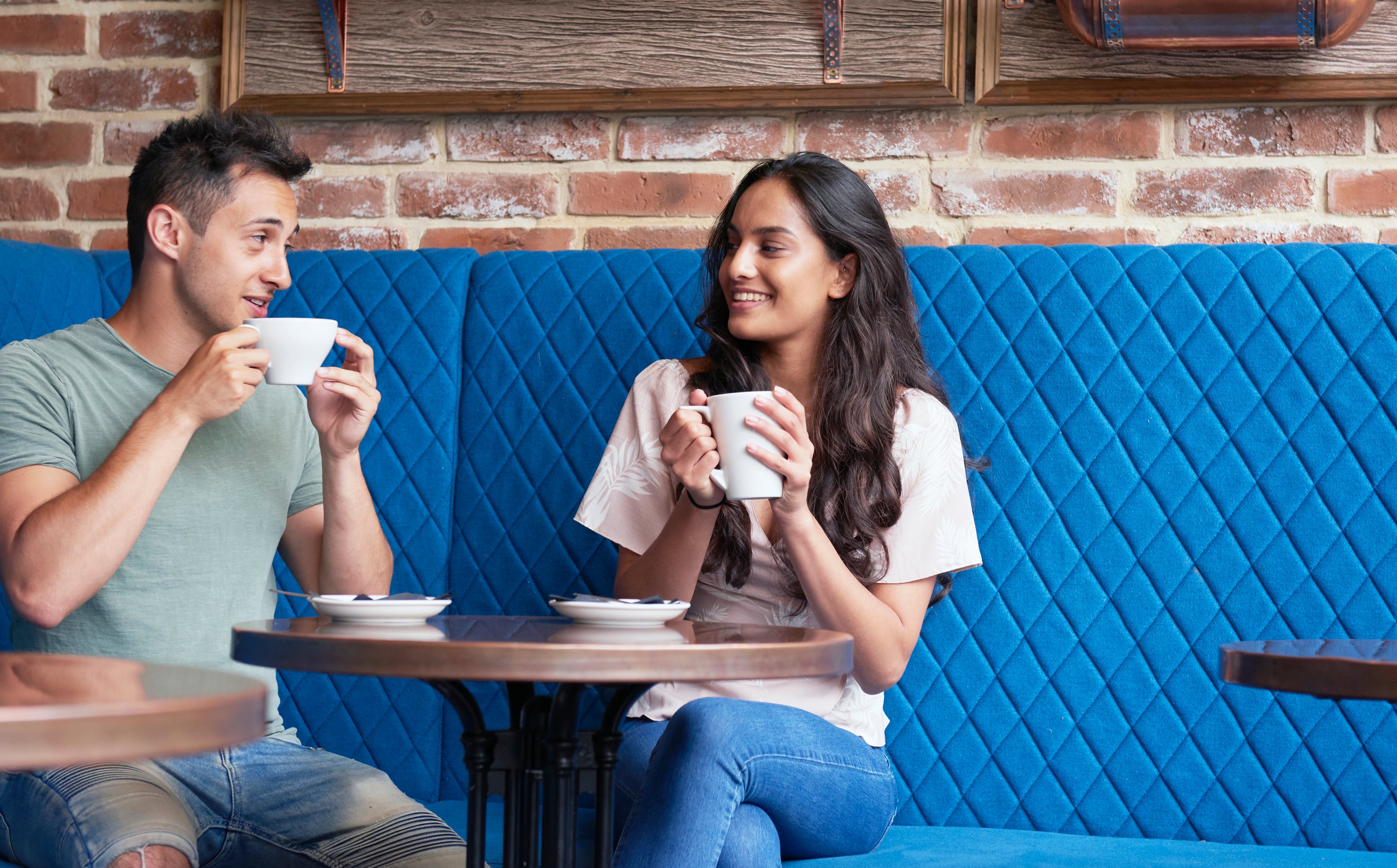 Two people drinking beverages at a cafe.