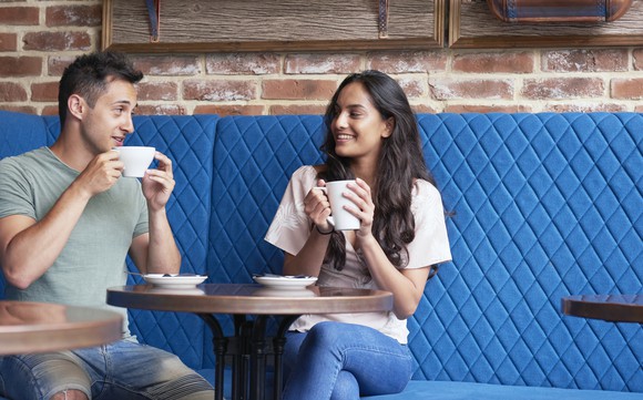 Two people drinking beverages at a cafe.