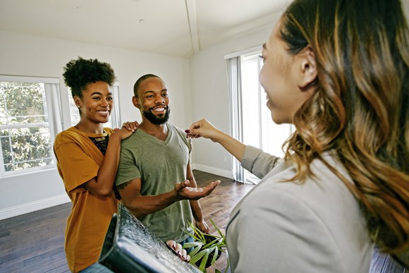 Couple being handed keys to a house by an agent.