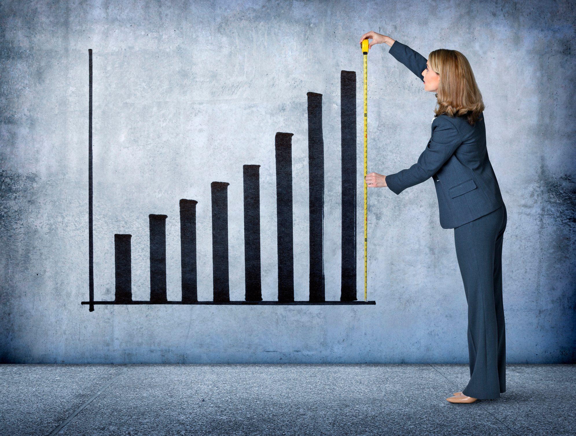 A person measuring a chart showing growth.