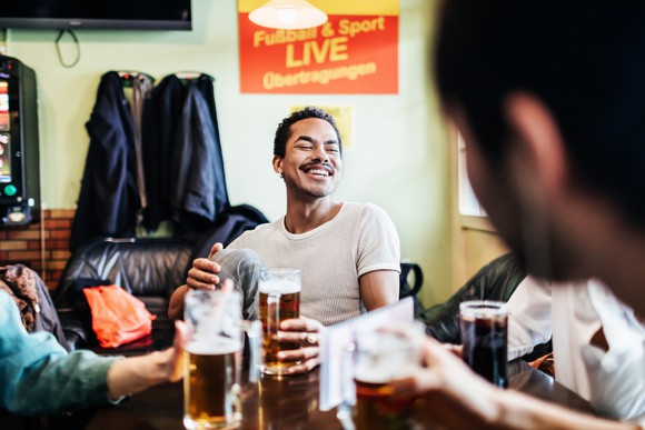 Group of friends with glasses of beer sitting around a table.