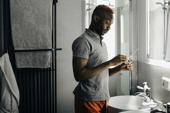 A person in a bathroom reading an at-home COVID test.