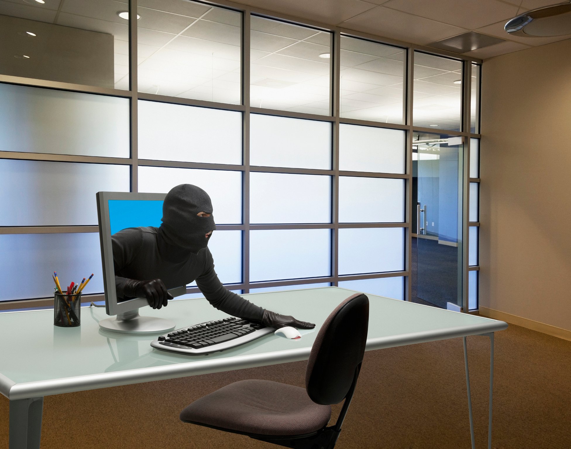 Person in black clothes and a black mask coming out of a computer screen.