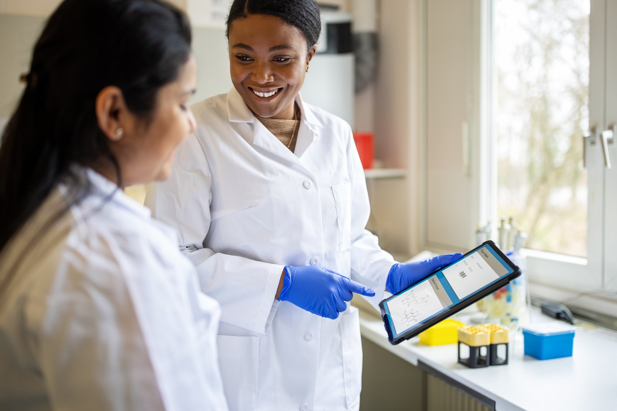 Two scientists work together on a tablet.