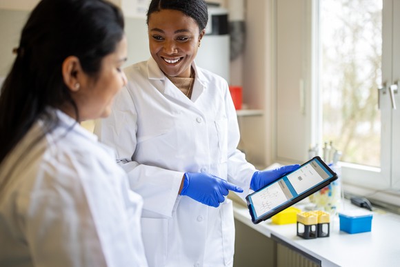 Two scientists work together on a tablet.