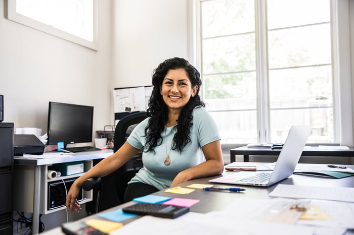 A woman sitting at her desk in her office, as if ready to help a client. 