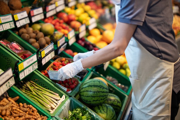 Grocery store worker adjusting a fresh produce display.