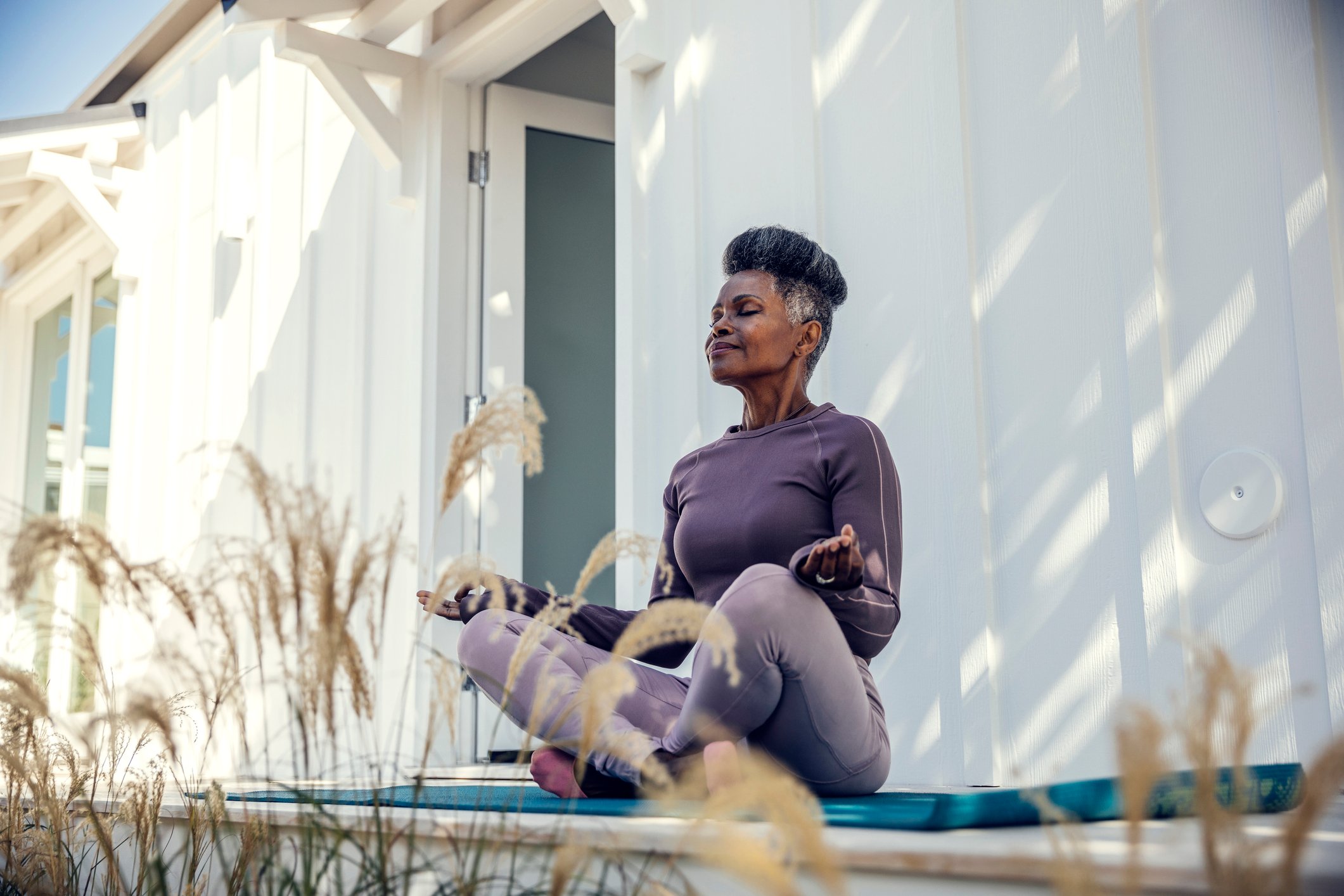 A person calmly meditates in her backyard.