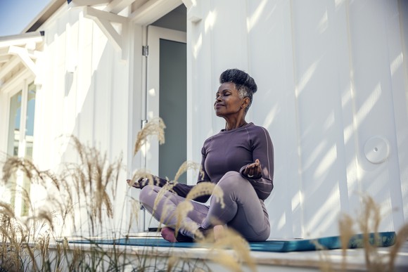 A person calmly meditates in her backyard.