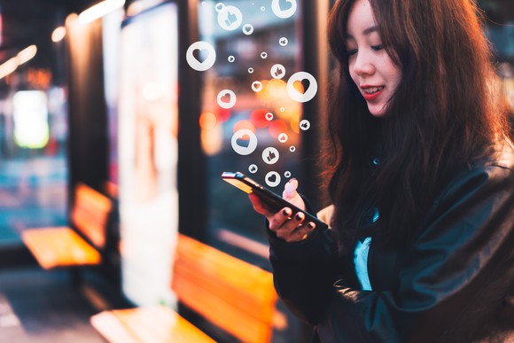 A person checking social media on their phone while standing by a shop. 