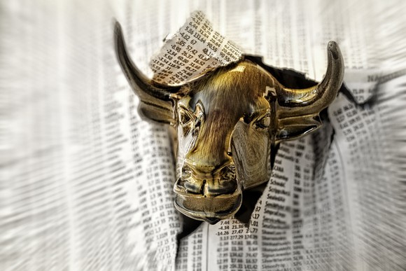 Bull head bursting through stock pages of newspaper