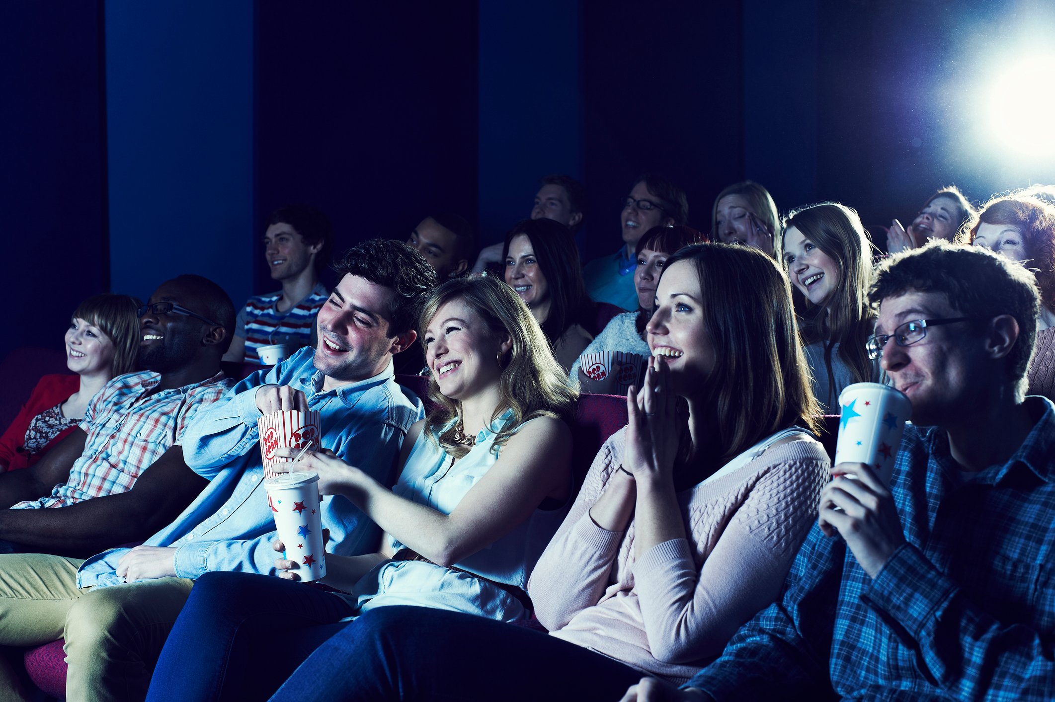 Folks smiling while watching something inside a theater.