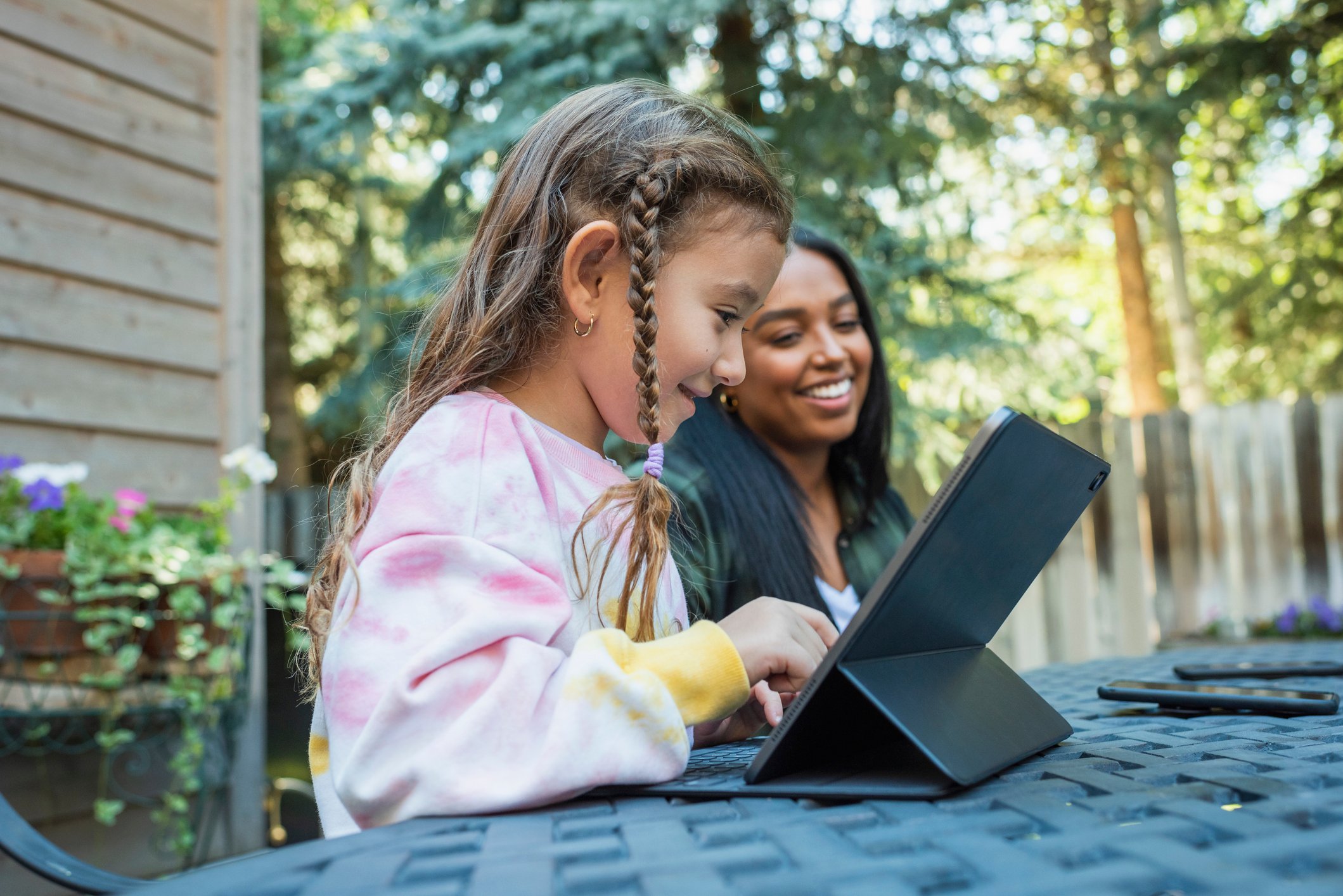 A child sits at a table using a tablet device.