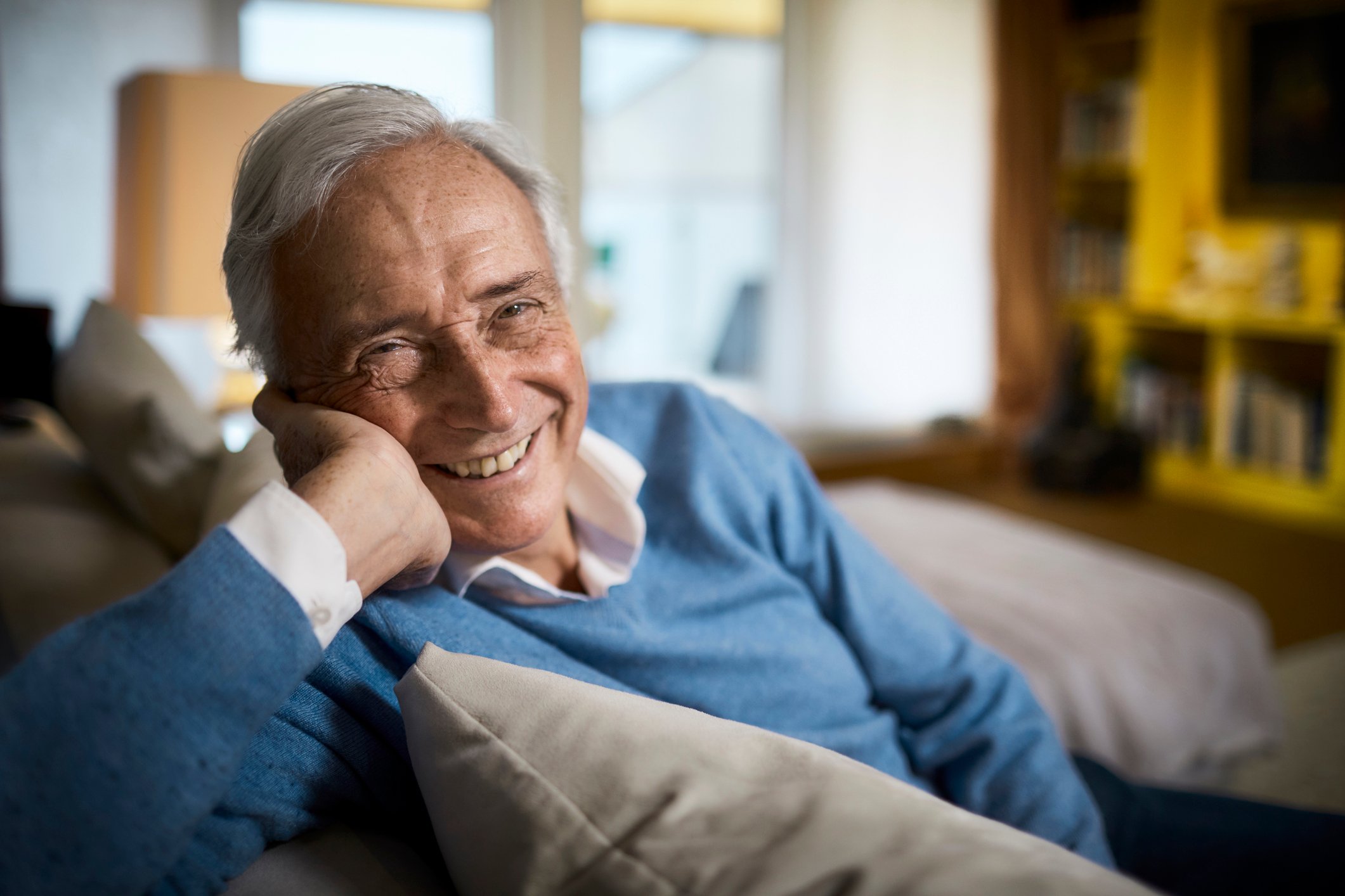 Retiree sitting on a couch and smiling.