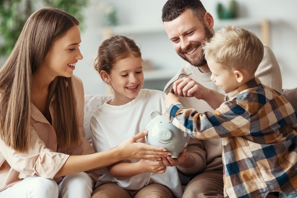 A family putting coins in a piggy bank.