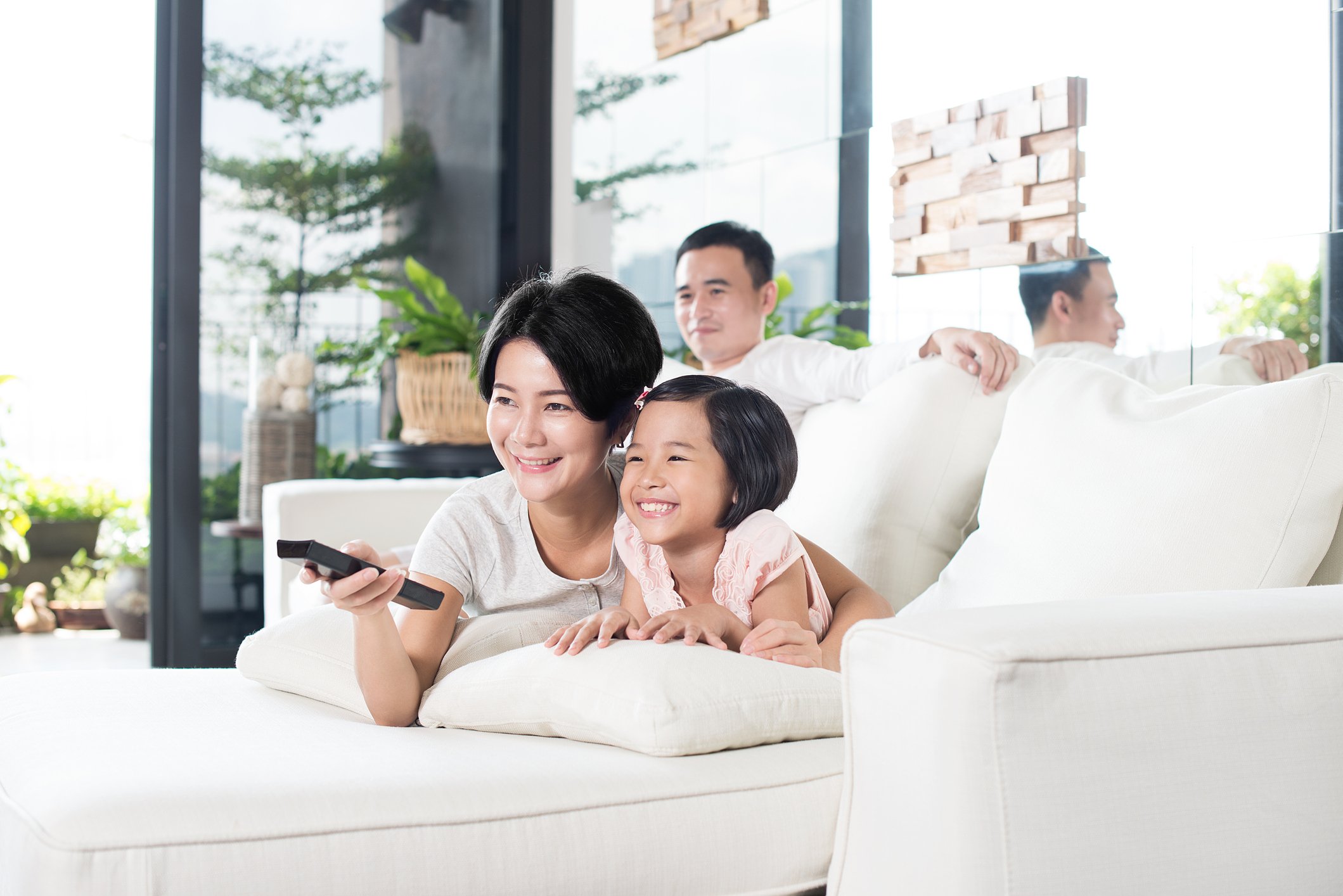 Young family laying on a couch watching TV.