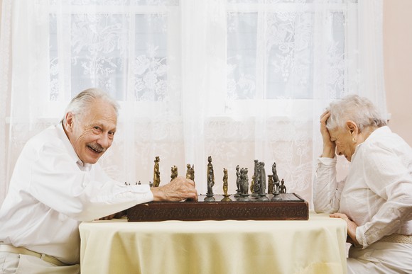 Two people playing chess, one happy, one disappointed.