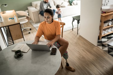 woman considers laptop with family in background